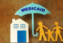 Paper cutout family with house under a Medicaid umbrella