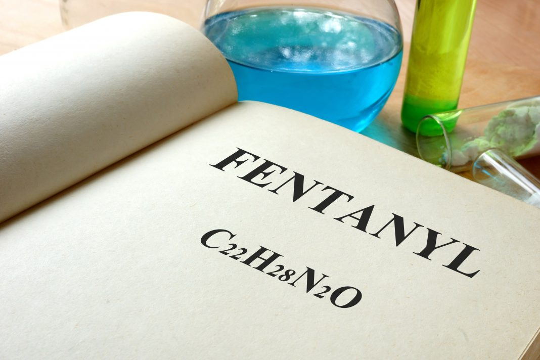 Book with fentanyl and test tubes on a table.