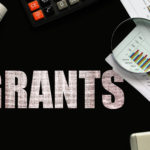 Text Grants on chalkboard with graphs, tables, calculations, calculator